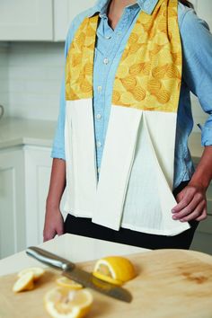 a woman standing in front of a cutting board with lemons on it and a knife