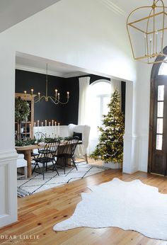 the dining room is decorated for christmas with white and gold decorations on the table, chandelier, and rug