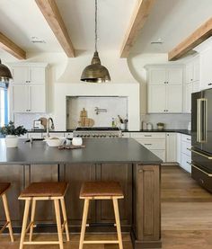 a large kitchen with two stools in front of the island and an oven on the other side