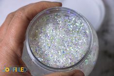 a hand holding a jar filled with glitter