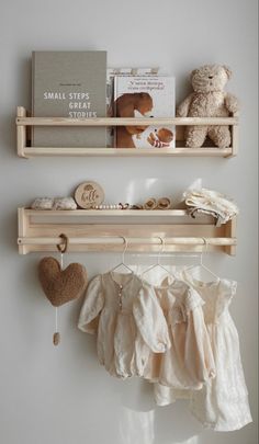 two wooden shelves with clothes and toys on them next to a book shelf filled with books