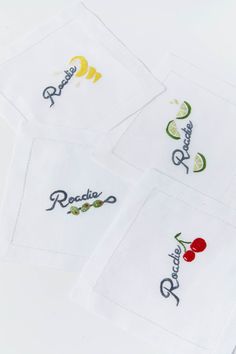 four embroidered cocktail napkins with fruit and vegetables on them, sitting next to each other