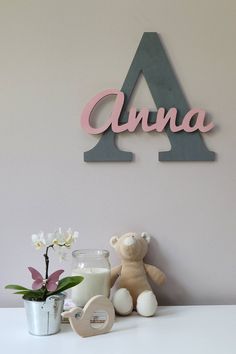 a teddy bear sitting on top of a white table next to a vase with flowers