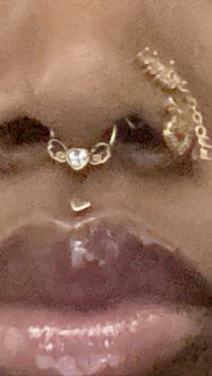 a woman's face with gold jewelry on her lip and nose ring in front of her mouth