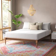 a white bed sitting on top of a wooden floor next to a window with lots of windows