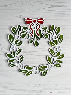 a christmas wreath cut out from paper on top of a white table with red and green decorations