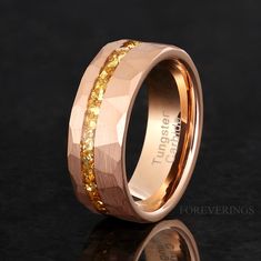 a wedding ring with gold glitter inlaying the center and inside, on a black surface