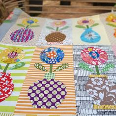 a quilted table top with flowers and stripes on the bottom, sitting on a wooden pallet