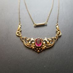 Antique Art deco brass gilded necklace  with fuschia glass faceted center stone Piece shows signs of tarnish and wear, glass stone has flee bites, see picture Length 42 cm Ornate Jeweled Necklaces, Ornate Jewel Pendant Necklace, Ornate Pendant Necklace With Jewels, Vintage Oval Jeweled Necklaces, Vintage Jeweled Oval Necklace, Vintage Oval Jeweled Necklace, Antique Yellow Gold Jeweled Necklaces, Ornate Jeweled Necklaces For Formal Occasions, Elegant Antique Gold Brass Necklaces