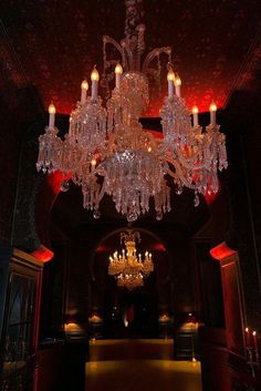 a chandelier hanging from the ceiling in a dark room with red lights on