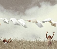 two children in a field flying kites with their hands up and one child standing on the grass