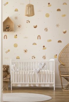 a baby's room with a white crib and gold wall decals on the walls