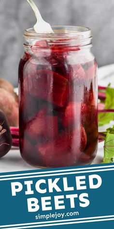 pickled beets in a glass jar with a spoon and radishes on the side