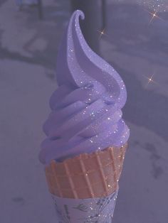 an ice cream cone with purple icing and sparkles