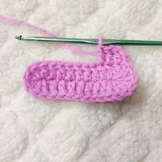 a pink crocheted object is being worked on by a pair of knitting needles