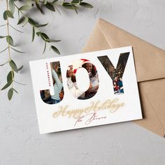 a greeting card with the words joy and images of people on it, sitting next to an envelope