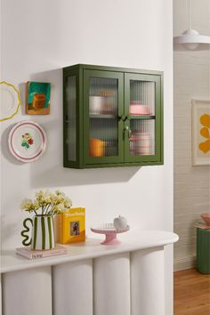 a green cabinet on the wall above a white table