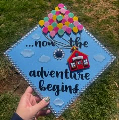 someone is holding up a graduation cap that says, now the adventure begins on it