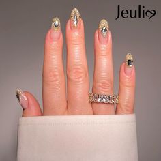 a woman's hand with gold and silver nail polishes on her fingers, holding a diamond ring