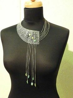 a black mannequin with a necklace on it's neck and beads hanging from the top