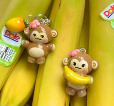 two monkey keychains sitting on top of bunches of bananas