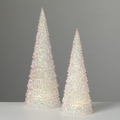 two small white christmas trees sitting on top of a table