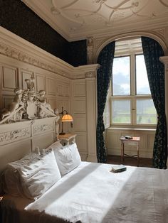 a large bed sitting in a bedroom next to a window with drapes on it