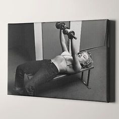 a black and white photo of a woman laying on a bench with two dumbbells