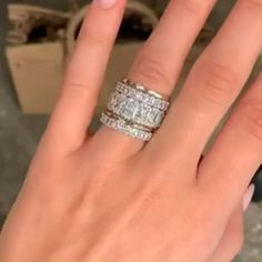 a woman's hand with two wedding bands on it and an engagement ring in the middle