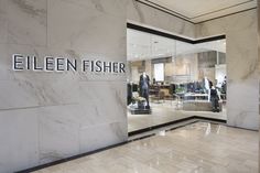 the entrance to an upscale clothing store with marble floors and large glass doors that read, ellen fisher