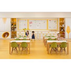 two children are playing with toys in the room that has yellow walls and green chairs