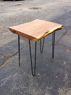 a wooden table with hairpin legs on the ground in front of a parked car