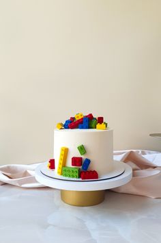 a white cake topped with legos on top of a table