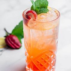 a close up of a drink in a glass with ice and strawberries on the side