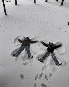 two people are laying in the snow with their hands out and footprints drawn on them