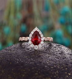 a close up view of a ring with a red stone in the middle and diamonds around it