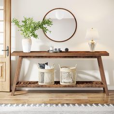 a wooden table with two baskets on it in front of a round mirror and door