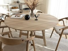 a round table with chairs around it and a vase filled with dried flowers on top