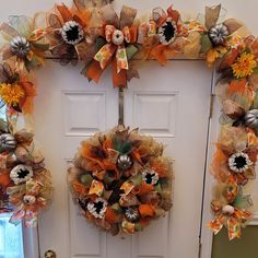 two wreaths on the front door decorated with pumpkins and other fall decor items