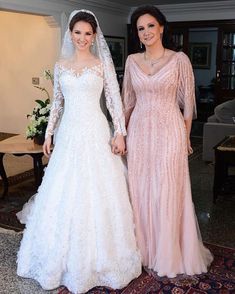 two women in wedding dresses standing next to each other on a carpeted room floor