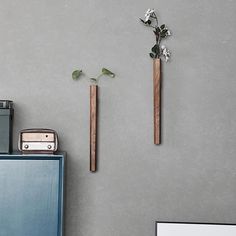 two wooden sticks are hanging on the wall next to a blue cabinet with flowers in it