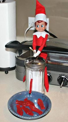 an elf is sitting on top of a stove next to a plate with ketchup