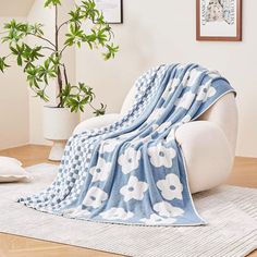 a blue and white blanket sitting on top of a chair next to a potted plant