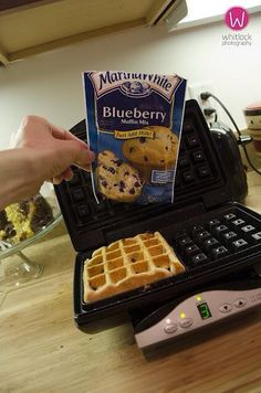 a waffle maker with blueberry cookies on top and a box of butter next to it