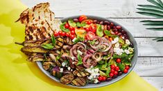 a salad with grilled meat and vegetables in a bowl on a yellow tablecloth