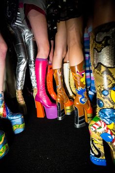 several women's colorful high heeled boots are lined up