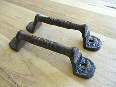 two old cast iron door handles on a wooden table