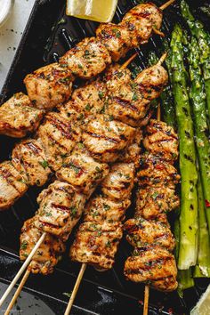 chicken and asparagus skewers on a grill with lemon wedges in the foreground