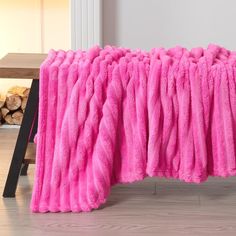 a large pink blanket sitting on top of a wooden floor next to a fire place