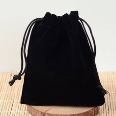 a black velvet bag sitting on top of a wooden table next to a piece of wood